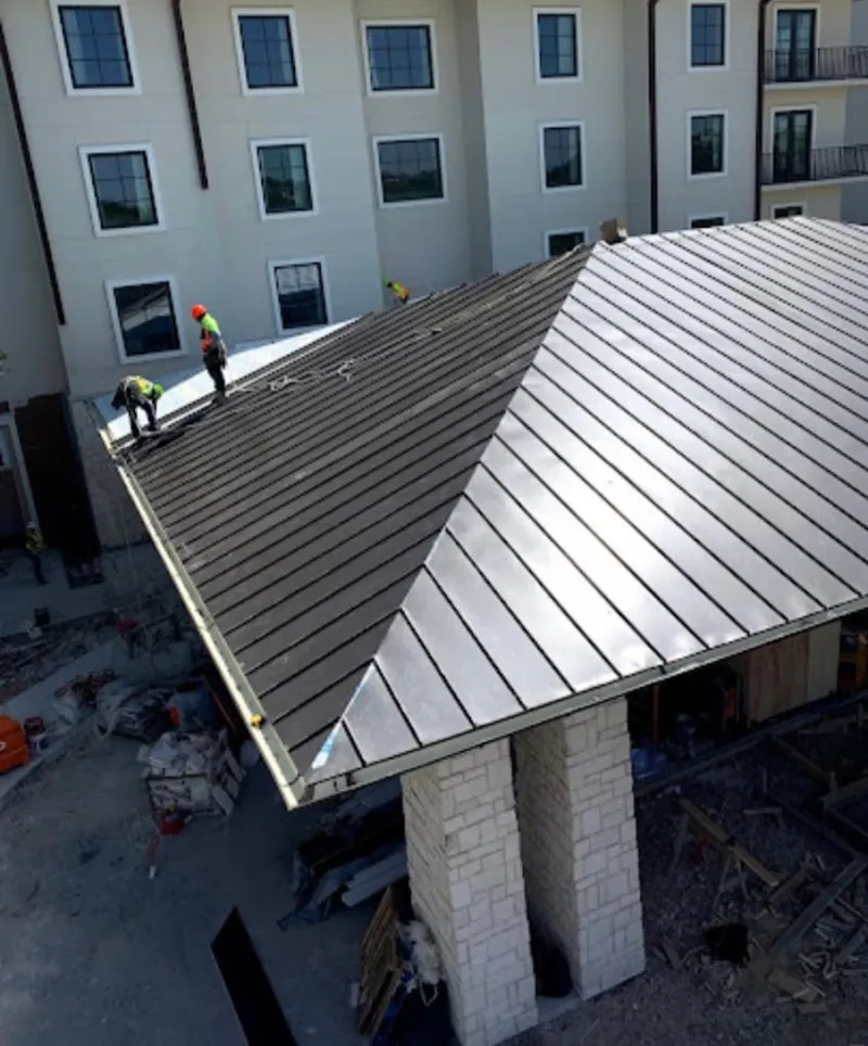 Crew installing standing seam metal roof panels on a commercial project in Waterboro